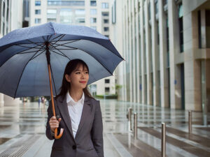 スーツを着て雨傘をさす若い女性