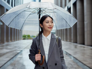 スーツを着て雨傘をさす若い女性