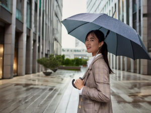 スーツを着て雨傘をさす若い女性