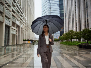 スーツを着て雨傘をさす若い女性