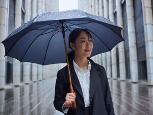 スーツを着て雨傘をさす若い女性