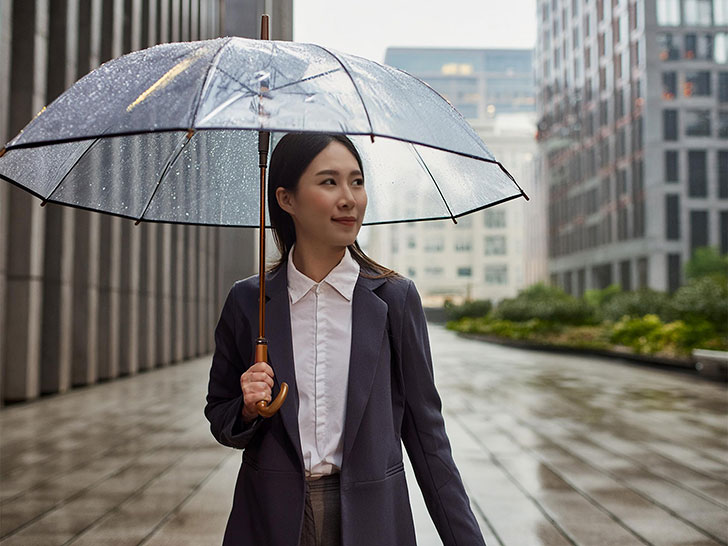 スーツを着て雨傘をさす若い女性