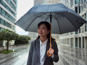 スーツを着て雨傘をさす若い女性