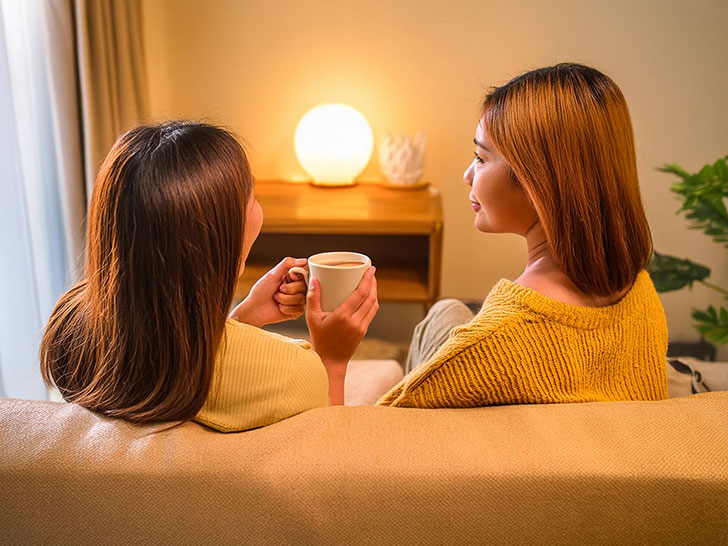 ソファに並んで座る女性カップルの後ろ姿