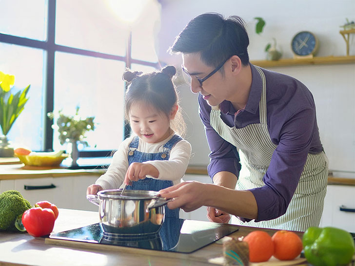 一緒に料理をするお父さんと小さな女の子