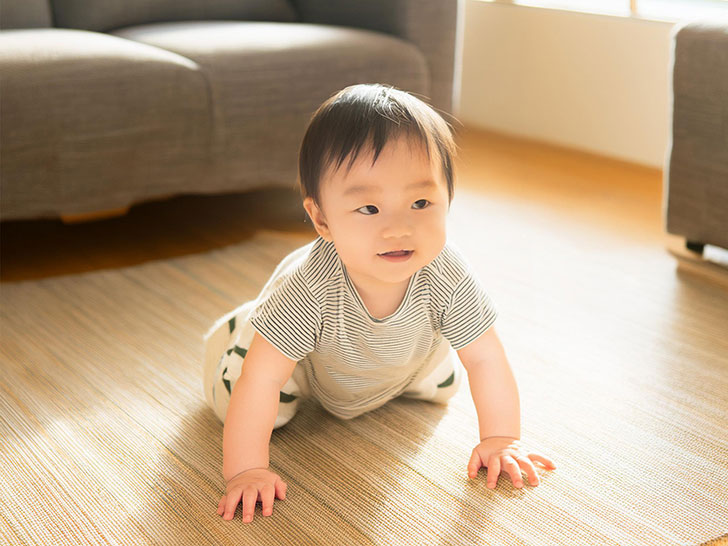 明るいリビングでハイハイするかわいい赤ちゃん