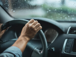 車のハンドルを握る男性の手