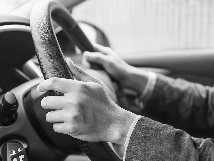 車のハンドルを握る男性の手