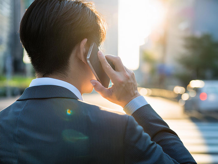 スマホで話す若いビジネスマンの後ろ姿