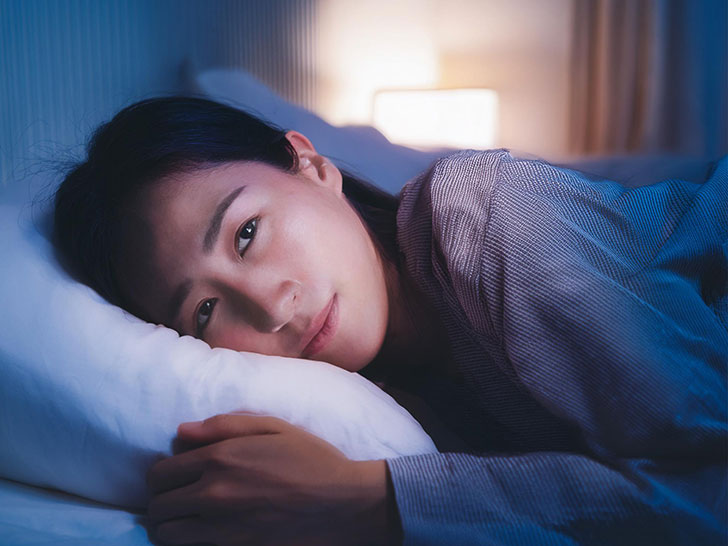 ベッドに横たわって眠れずにいる若い女性