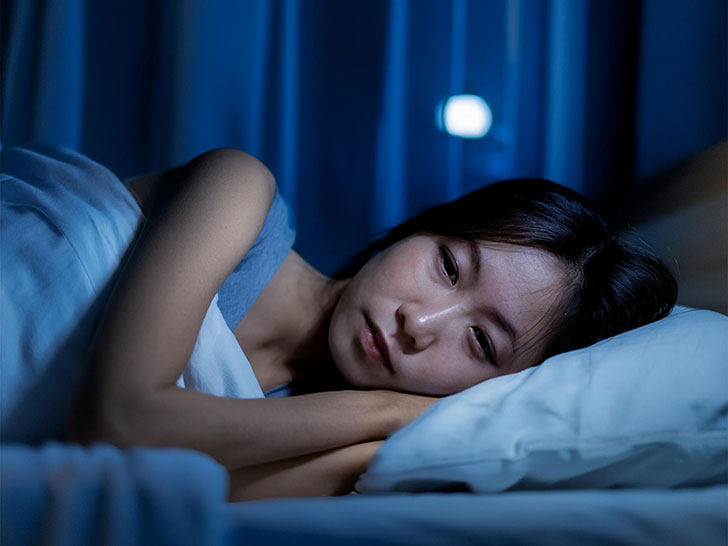 ベッドに横たわって眠れずにいる若い女性