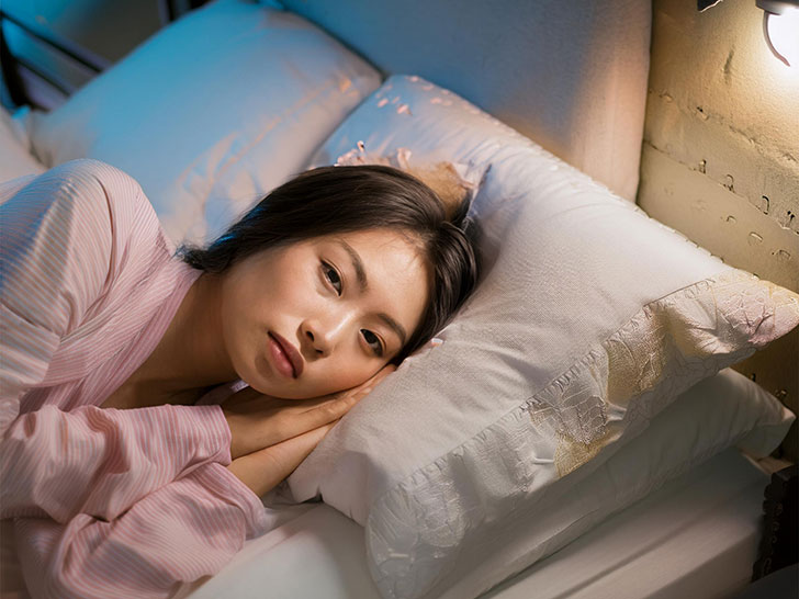 ベッドに横たわって眠れずにいる若い女性