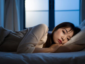 ベッドに横たわって眠れずにいる若い女性