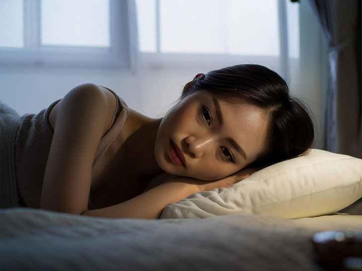 ベッドに横たわって眠れずにいる若い女性