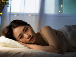 ベッドに横たわって眠れずにいる若い女性