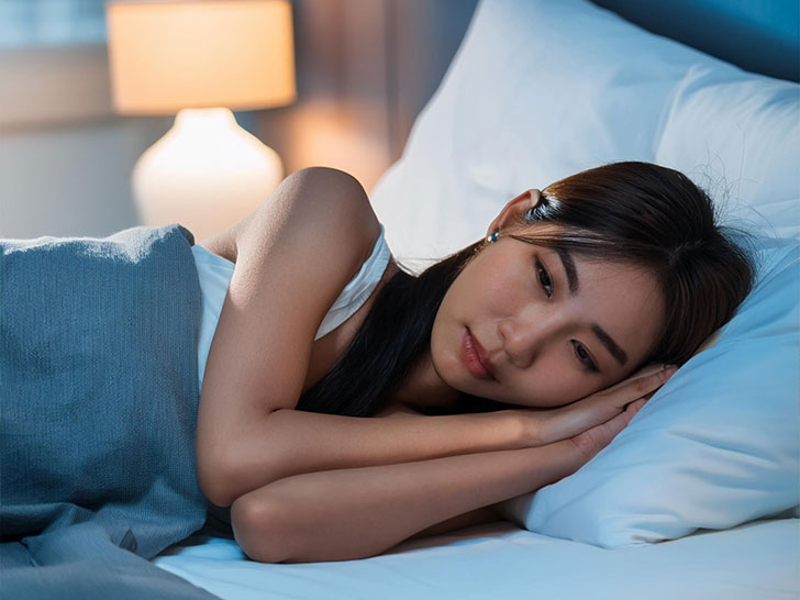 ベッドに横たわって眠れずにいる若い女性