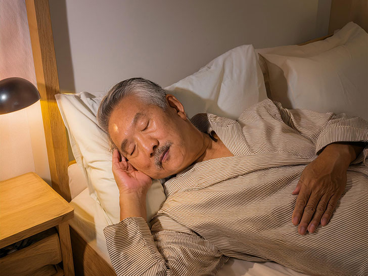 ベッドで眠るシニア男性