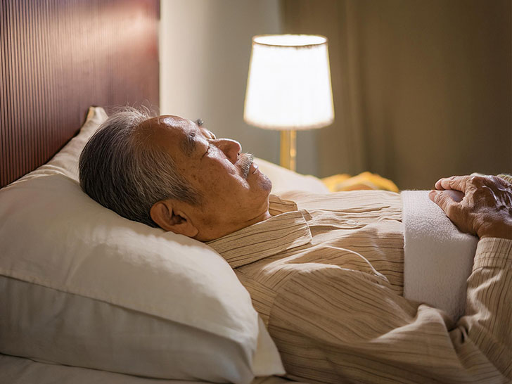 ベッドで眠るシニア男性