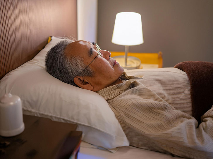 ベッドで眠るシニア男性