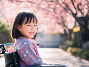 車椅子に座り笑顔を見せる小学生の女の子