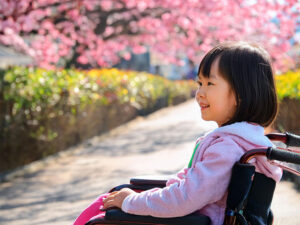 車椅子に座り笑顔を見せる小学生の女の子