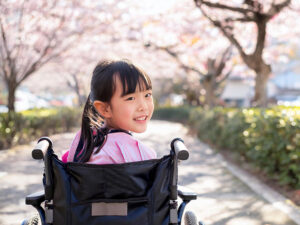 車椅子に座り笑顔を見せる小学生の女の子