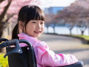 車椅子に座り笑顔を見せる小学生の女の子