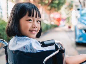 車椅子に座り笑顔を見せる小学生の女の子