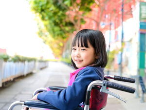 車椅子に座り笑顔を見せる小学生の女の子