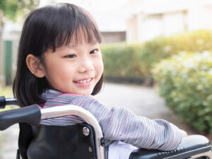 車椅子に座り笑顔を見せる小学生の女の子