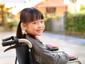 車椅子に座り笑顔を見せる小学生の女の子