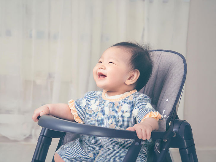 椅子に座って笑うかわいい赤ちゃん