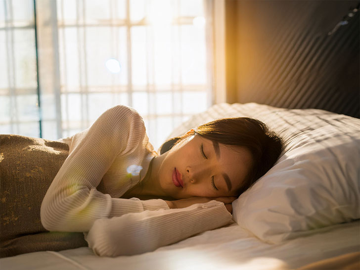 ベッドで眠る若い女性