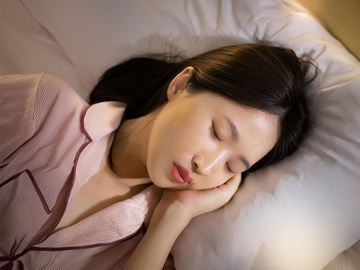 ベッドで眠る若い女性