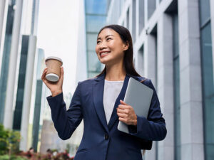 コーヒーを片手にオフィス街にたたずむ女性