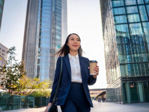 コーヒーを片手にオフィス街にたたずむ女性