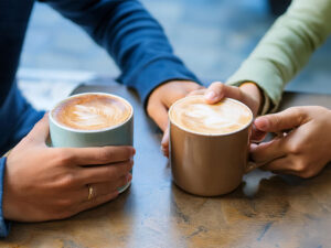 カフェラテの前で重ねられたカップルの手