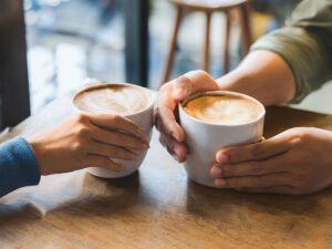 カフェラテの前で重ねられたカップルの手