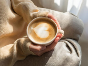 カフェラテのマグカップを持つ女性の手