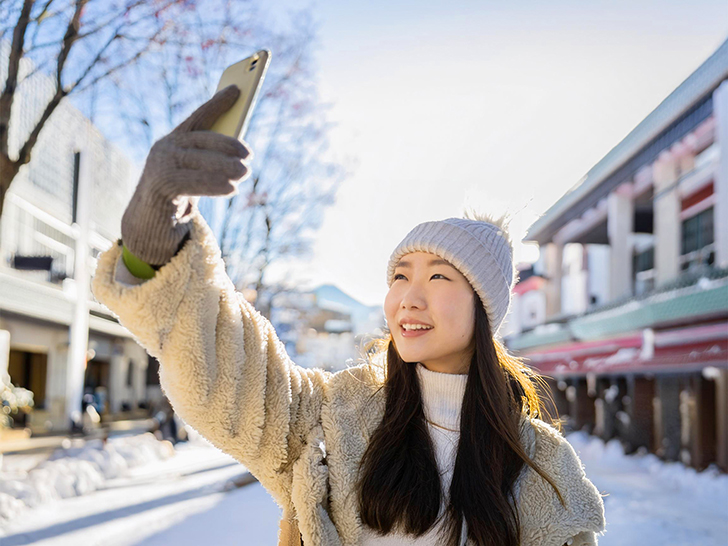 冬の観光地で自撮りをする若い女性