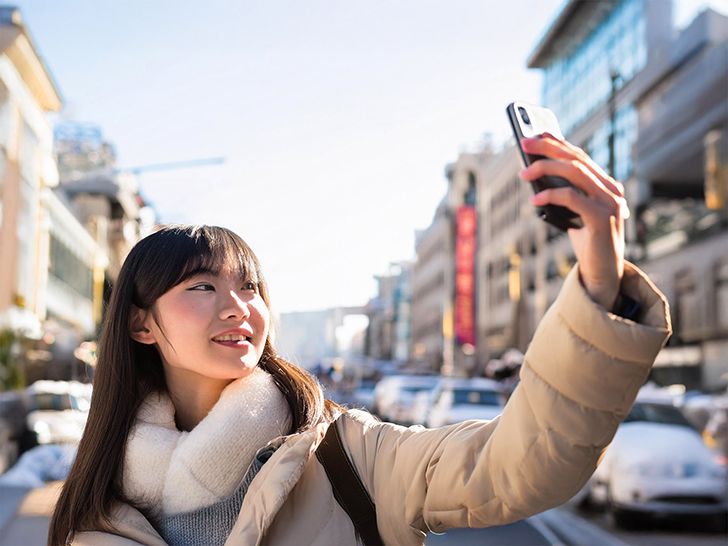 冬の観光地で自撮りをする若い女性