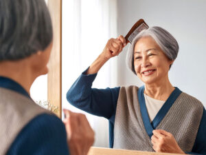 鏡の前でブラッシングするシニア女性