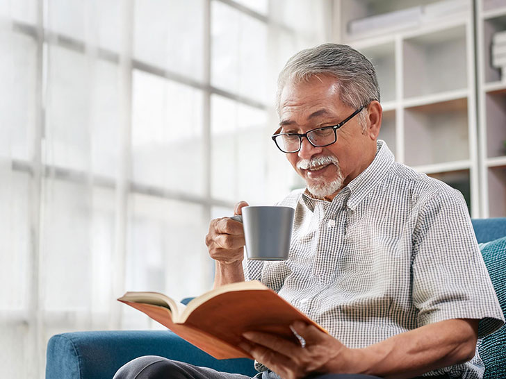 コーヒーを飲みながら読書をするシニア男性