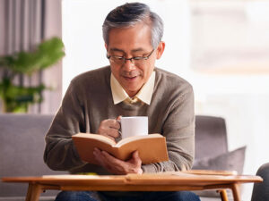 コーヒーを飲みながら読書をするシニア男性