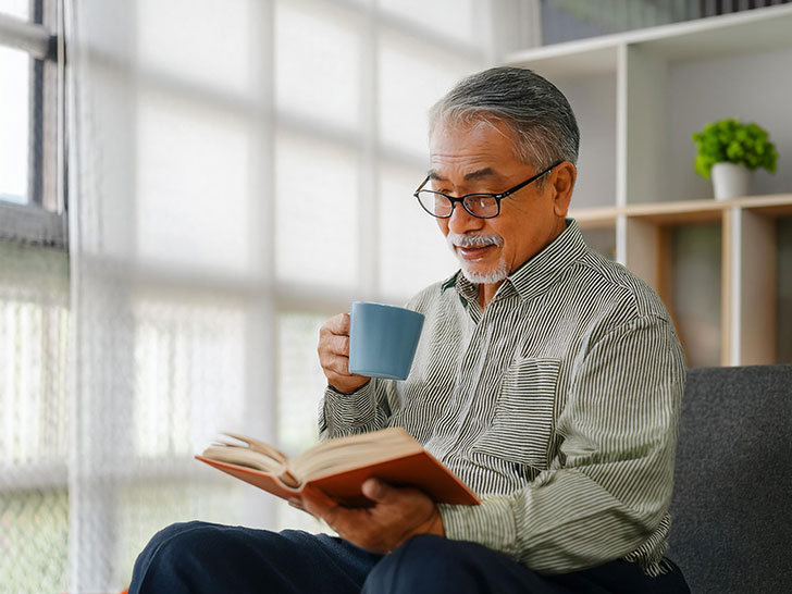 コーヒーを飲みながら読書をするシニア男性