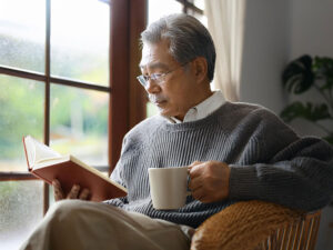 コーヒーを飲みながら読書をするシニア男性