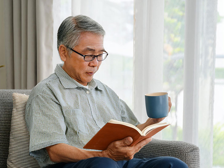 コーヒーを飲みながら読書をするシニア男性