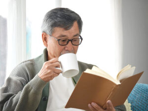 コーヒーを飲みながら読書をするシニア男性