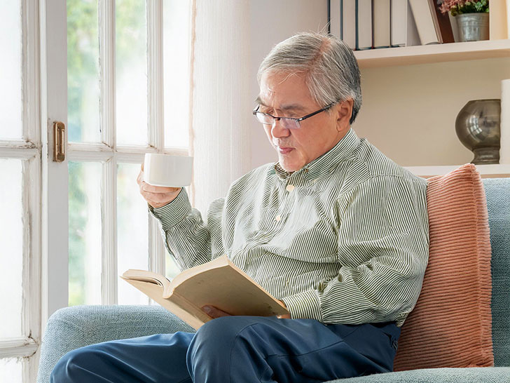 コーヒーを飲みながら読書をするシニア男性