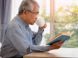 コーヒーを飲みながら読書をするシニア男性